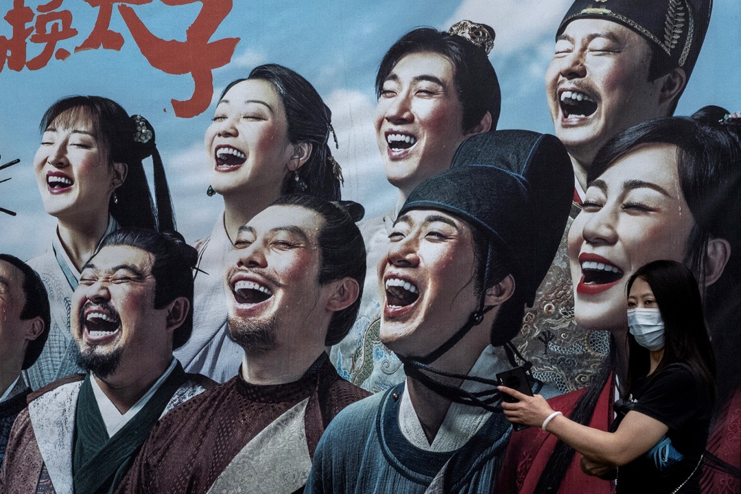2022年7月,中国北京,一名戴口罩的女子在一幅电影海报前拍照。