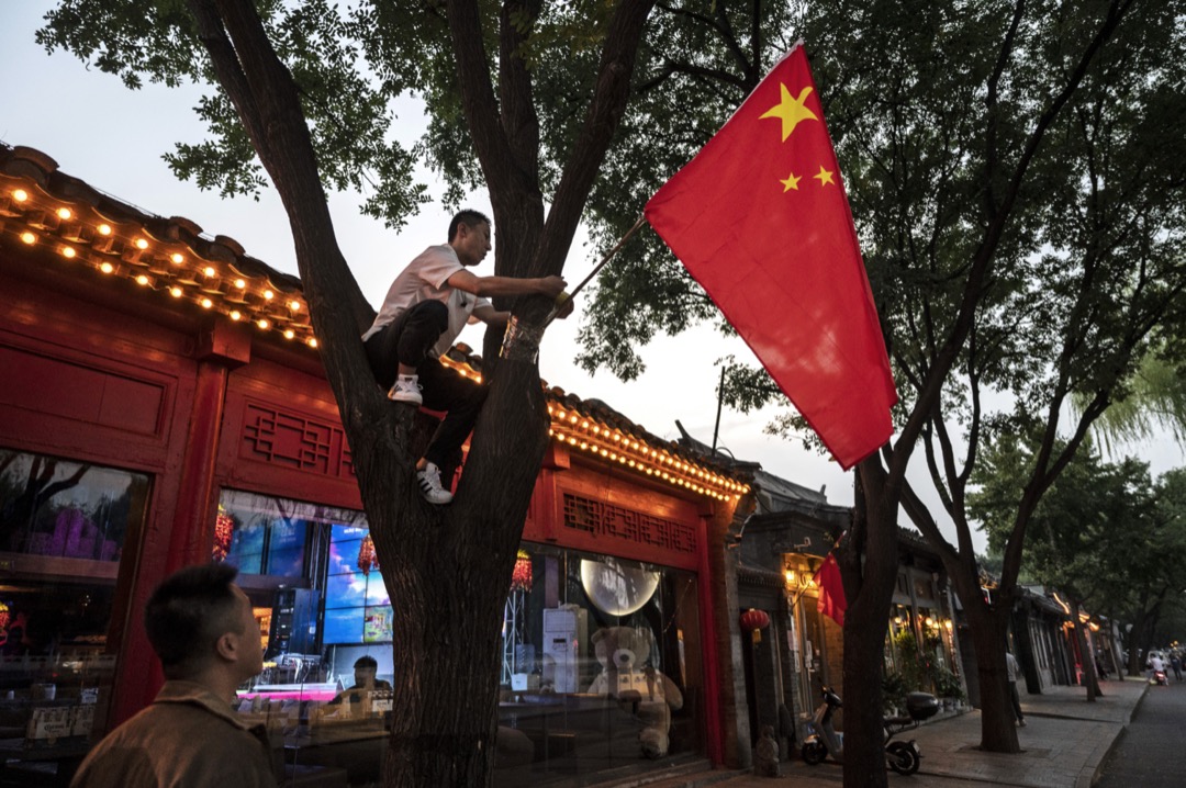 2022年9月28日,中国国庆日前夕,一名男子在北京街头挂起一支中国国旗。