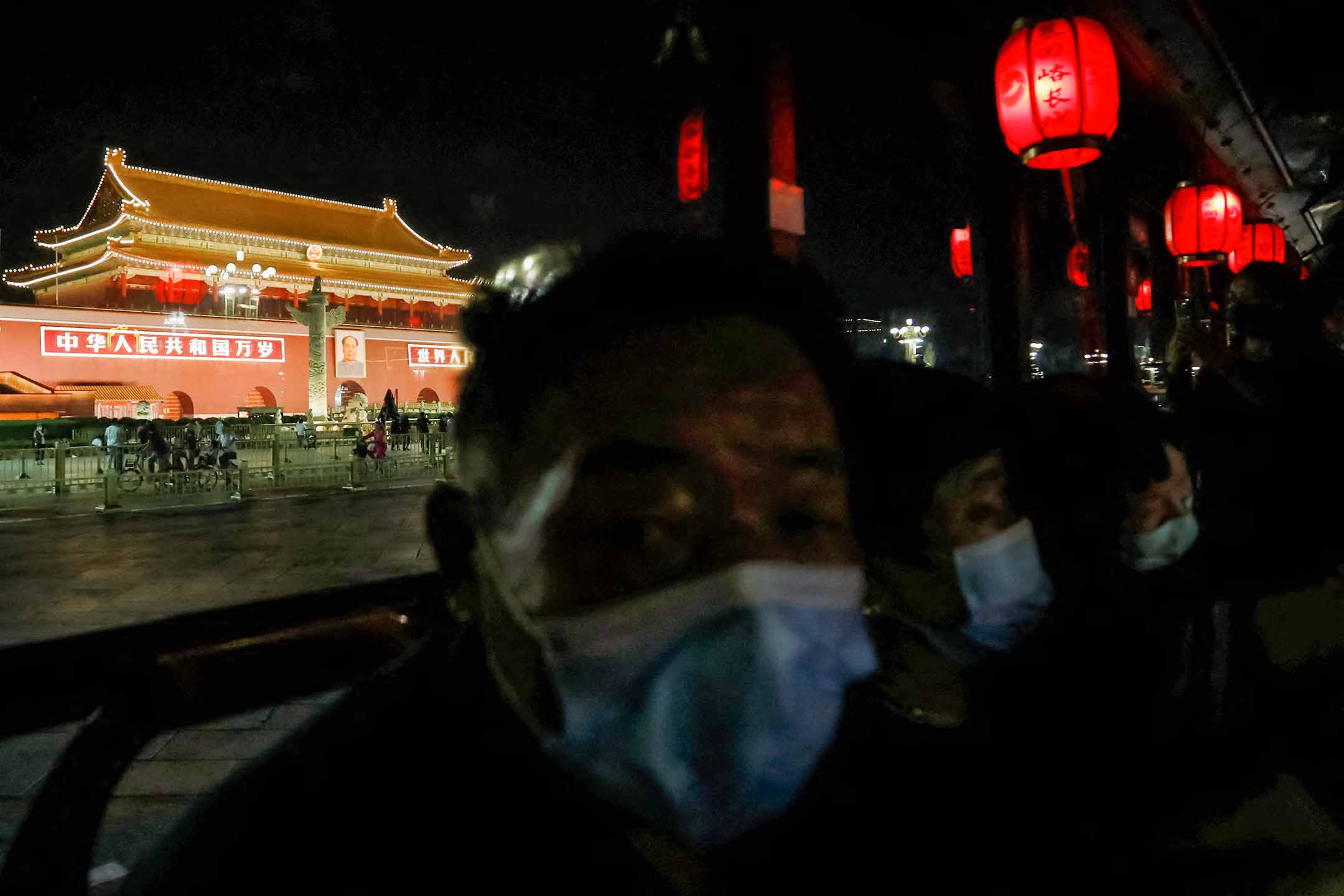 2022年9月26日,北京国庆节前夕,戴著口罩的乘客坐在观光巴士上,夜游经过天安门。