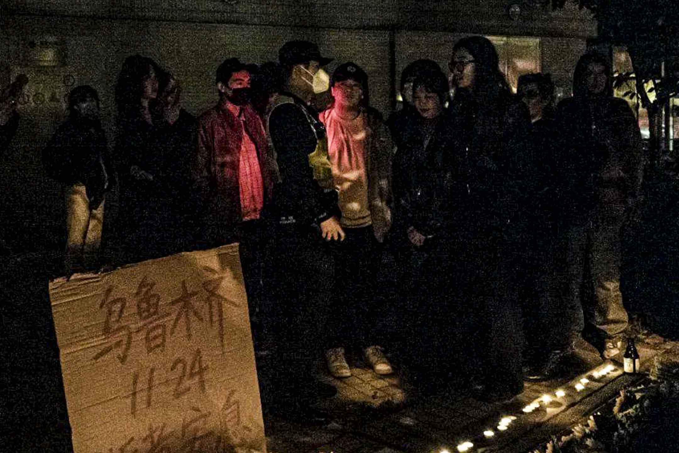 2022年11月26日深夜,上海烏魯木齊中路聚集大量市民,悼念11.24烏魯木齊火災10位逝者,有人人們在街道上點燃蠟燭,獻上鮮花。