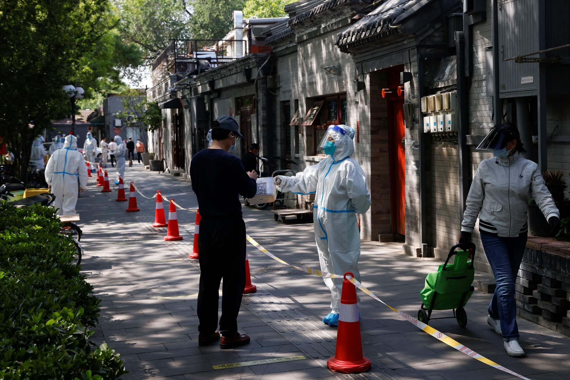 2022年5月3日,中國北京,一名穿保護衣的防疫人員要求一名前往進行核酸檢測的居民先掃一個二維碼。