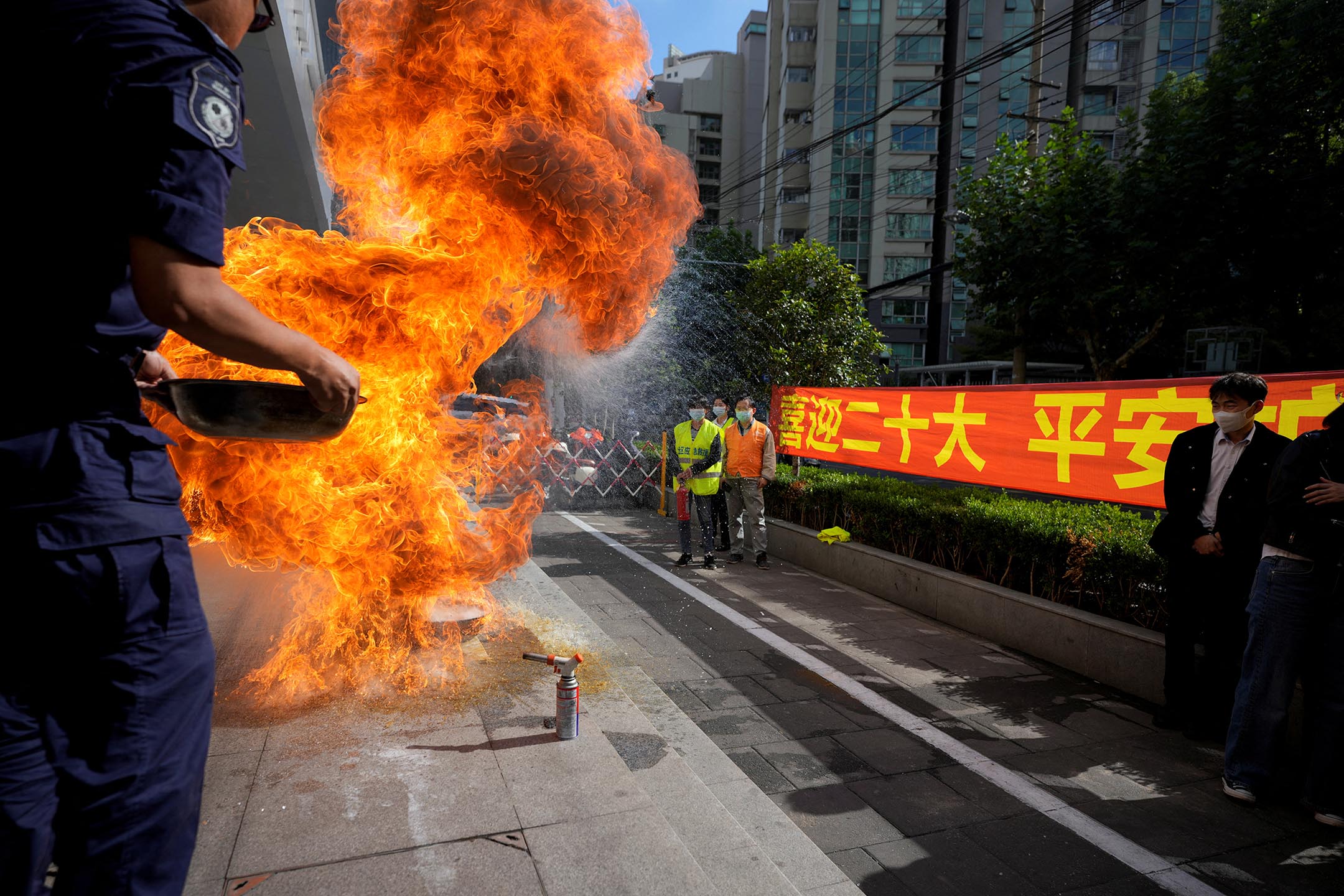 2022年10月13日，中國上海的一個住宅區，人們在中國共產黨第二十次全國代表大會的橫幅旁參加緊急演習。攝：Aly Song/Reuters/達志影像