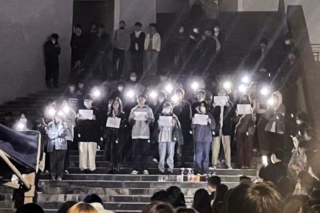 2022年11月26日晚上,大批南京传媒学院学生在校园钟楼前聚集,手举白纸、打开手机闪光灯集会,纪念在新疆乌鲁木齐大火中遇难的民众。