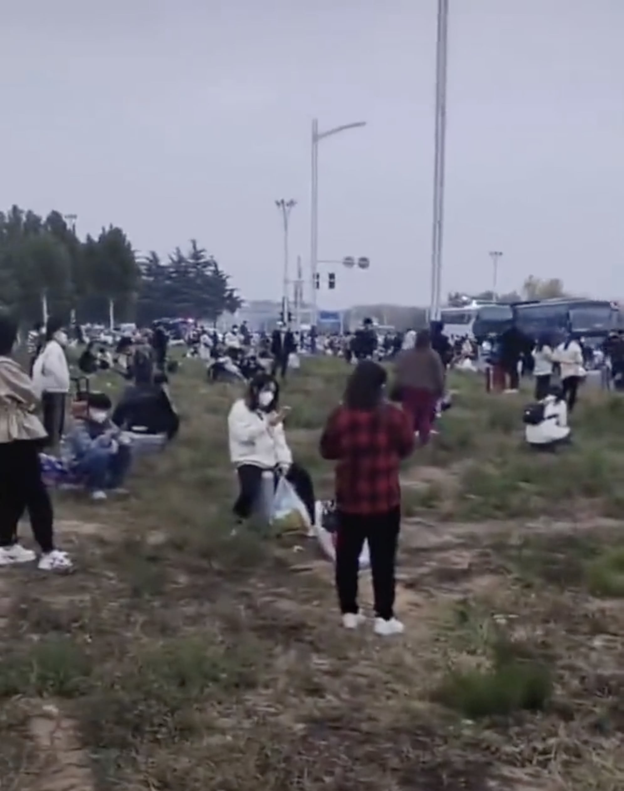 中國河南鄭州,逃離富士康廠區的員工在公路旁的草坪等候車輛接送回家。