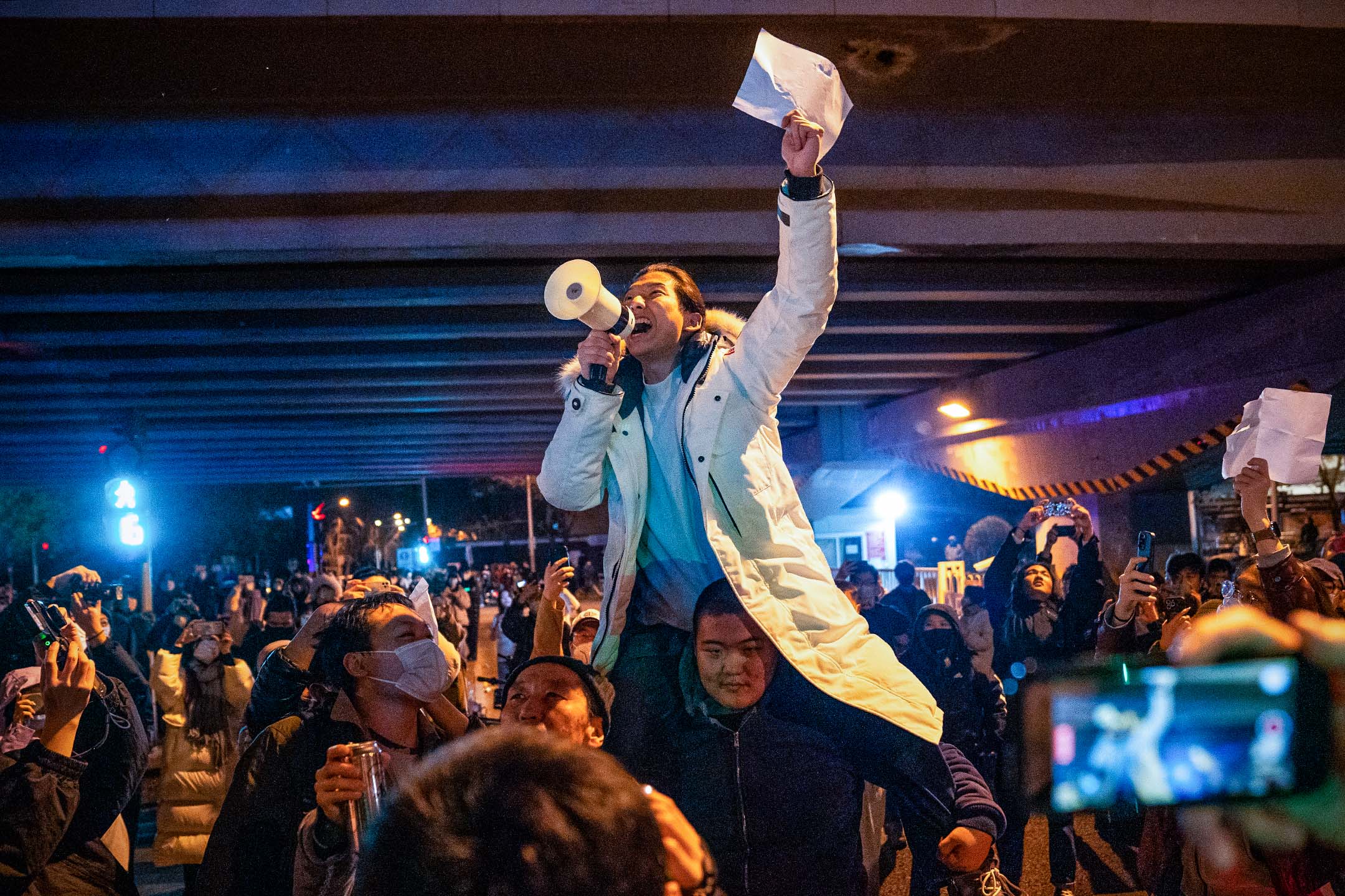 2022年11月28日,北京的示威活动中,一名示威者举著白纸并高喊口号。在街头和大学校园,反对封控的抗议蔓延中国各地。图:Bloomberg via Getty Images