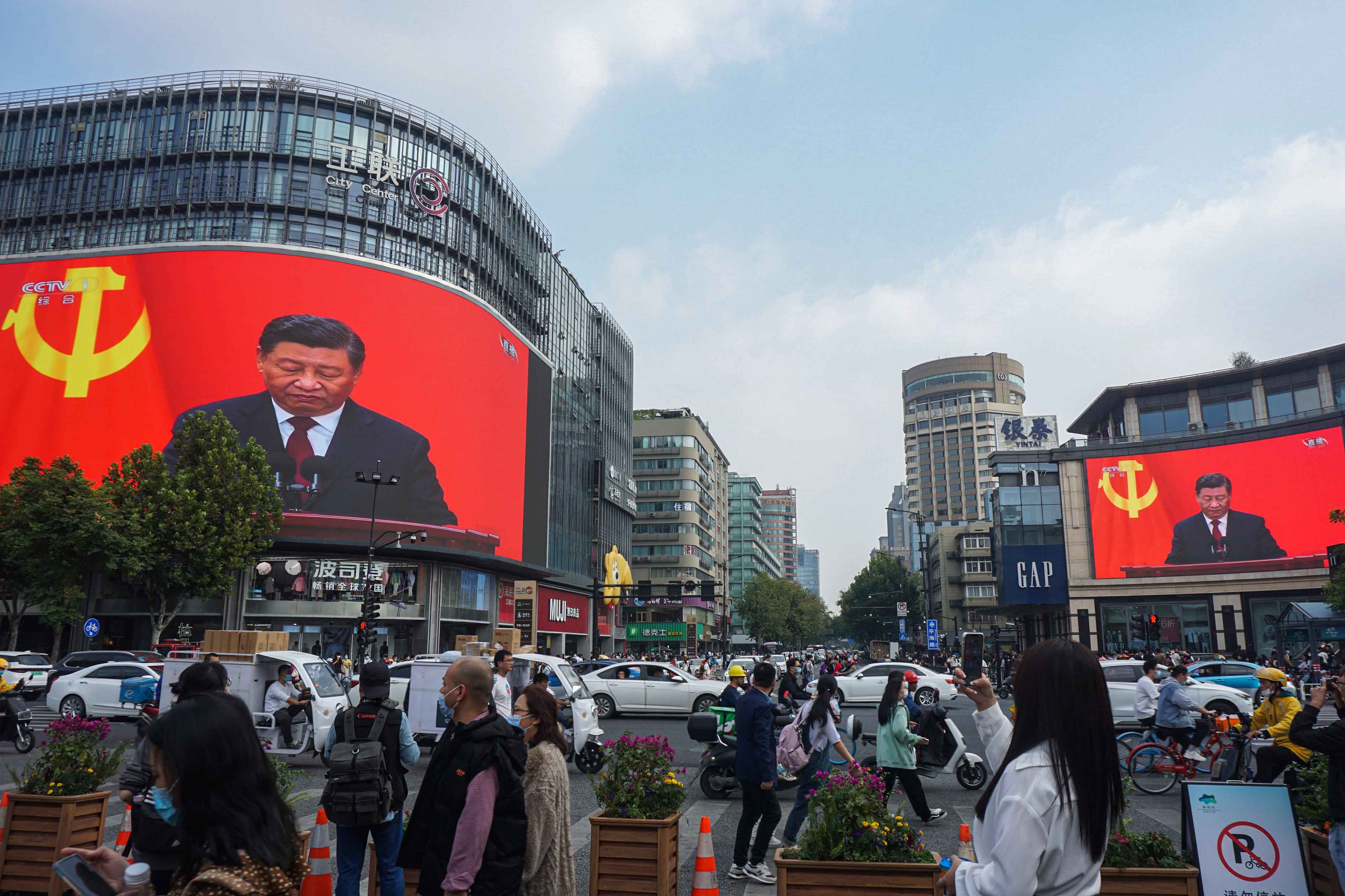 2022年10月23日,杭州,人们经过一个十字路口,巨大的屏幕播放习近平在共产党第二十次全国代表大会闭幕式上的讲话。