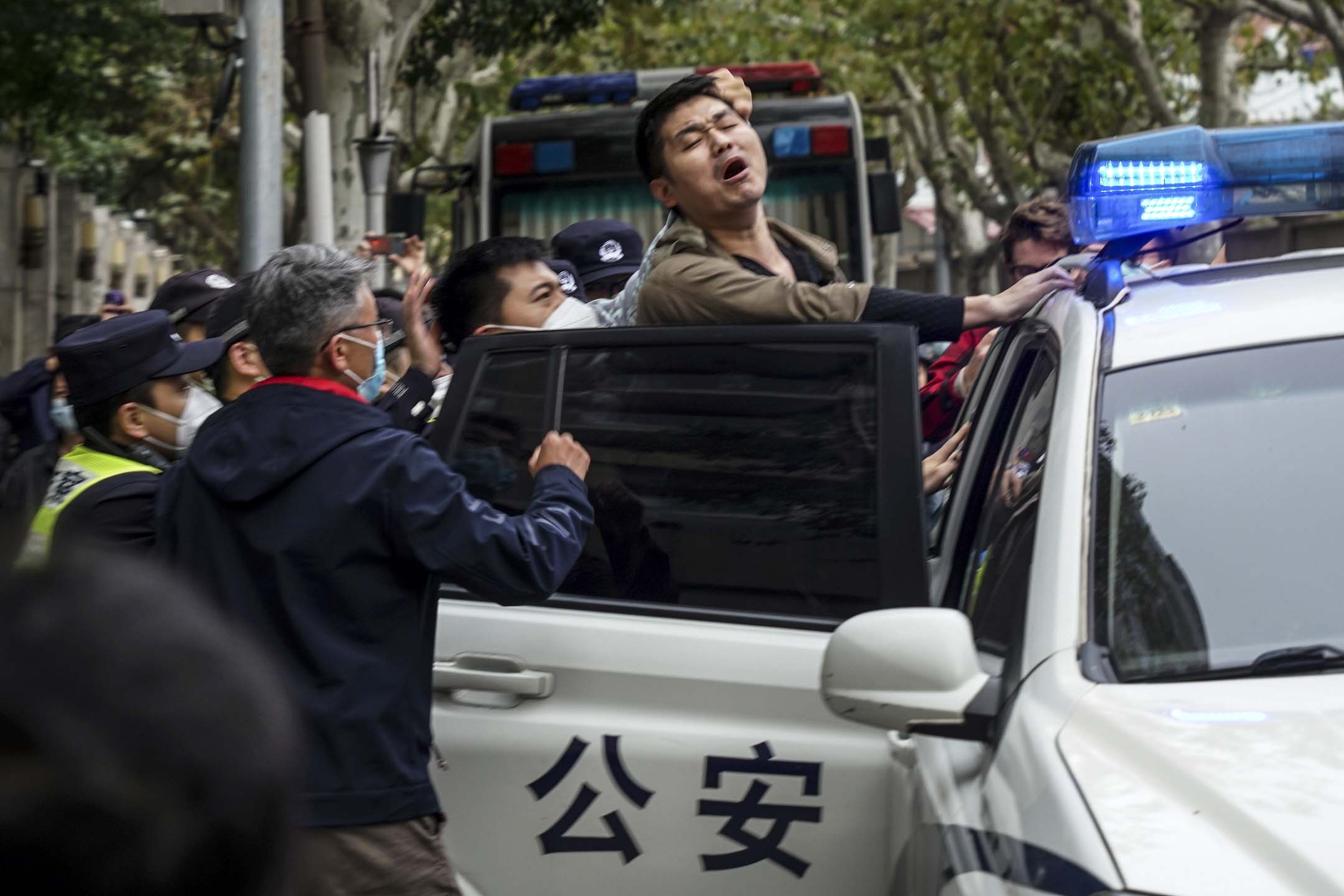 2022年11月27日,上海的示威現場,一名示威者被警察逮捕並被押上警車。
