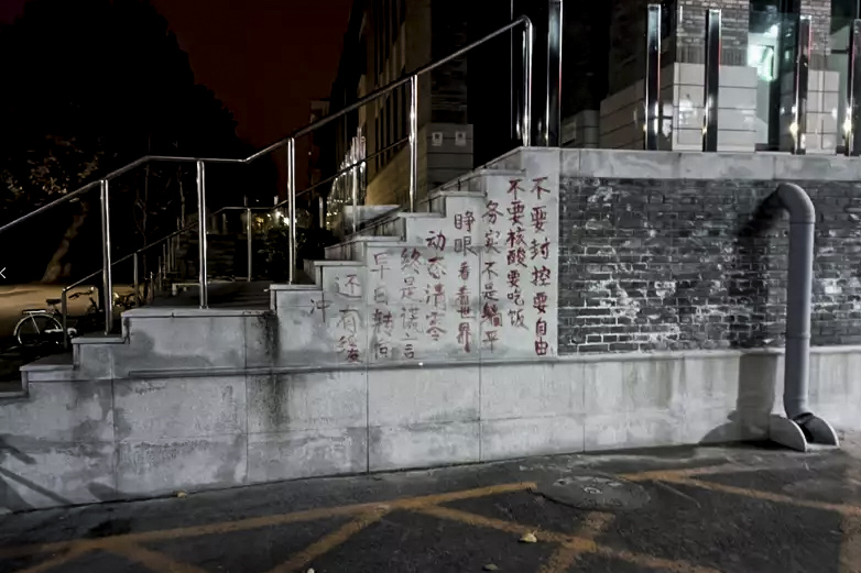 2022年11月27日,北京大学食堂附近的墙壁出现红色涂鸦文字,写著示威文字。