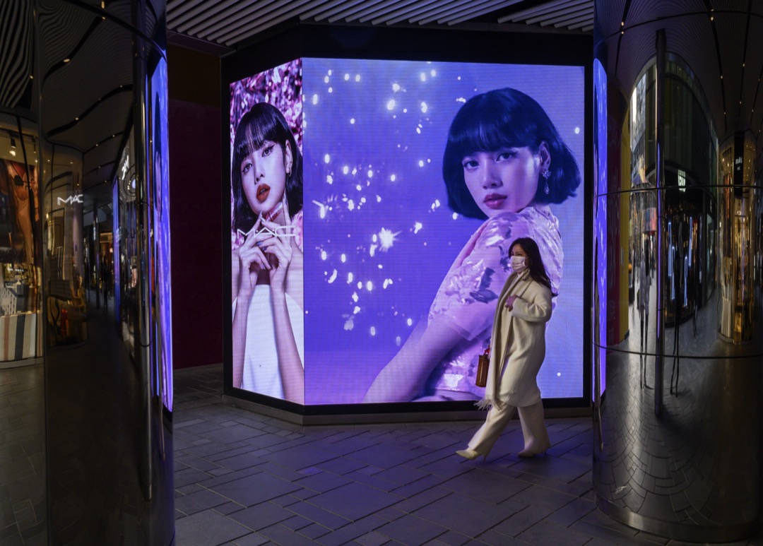 中國北京,一名女子走過一塊廣告版。