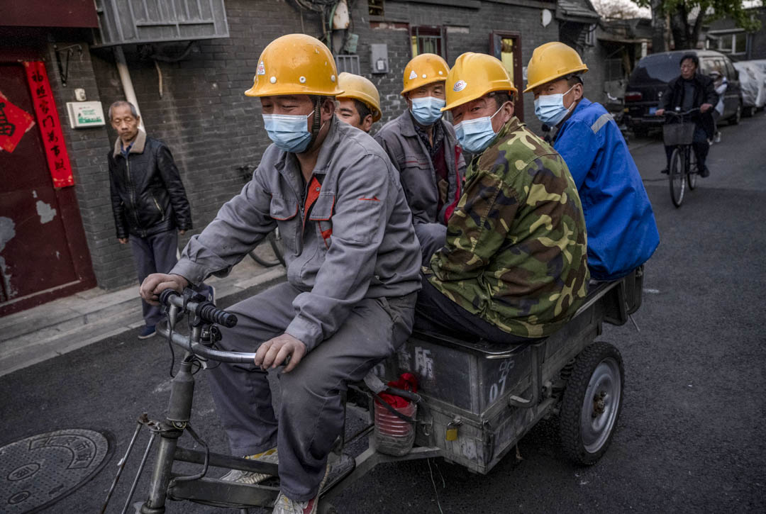 2021年4月14日,中國北京的建築工人騎著三輪車在街上行走。