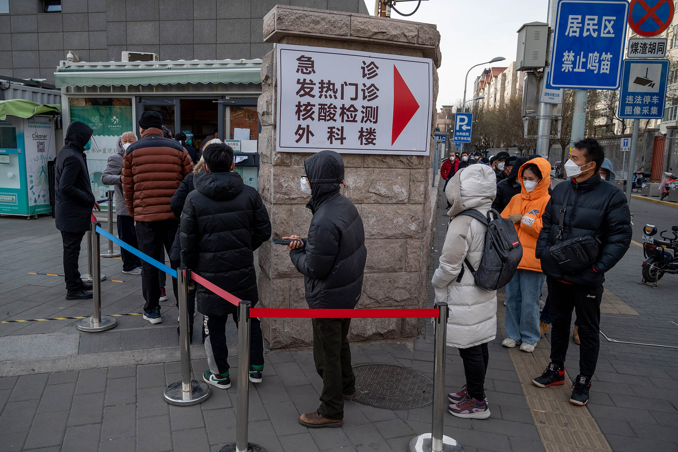 2022年12月14日,北京,人們在進入一家醫院之前排隊購買快速抗原檢測試劑盒。
