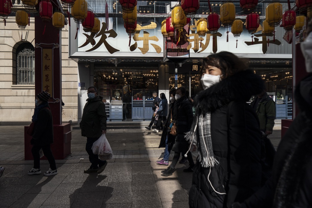2023年1月25日,中國蘇州,戴口罩的市民在農曆新年期間在一條商業街走過。