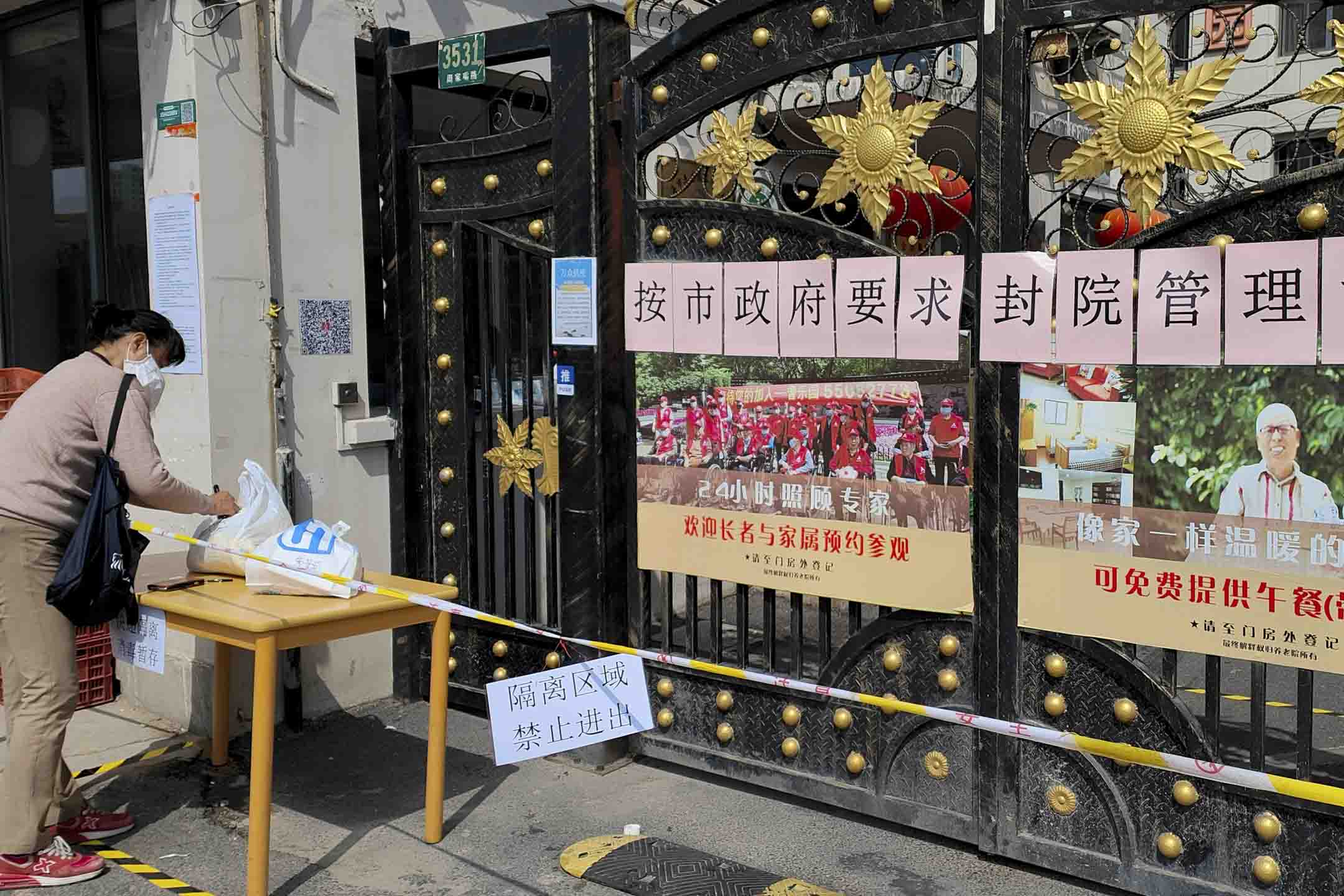 2022年3月30日,中國上海,一名婦女在療養院門口的袋子上寫字,該療養院以疫情為由拒絕訪客。