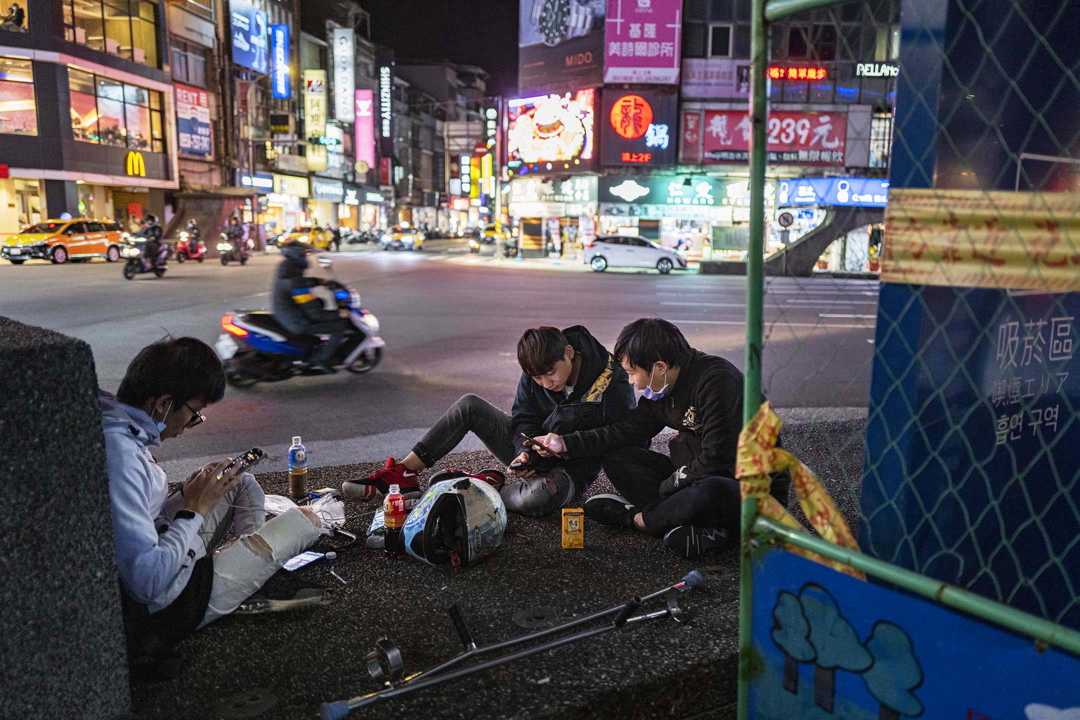 2021年11月10日,基隆,年轻人坐在路旁玩手机。