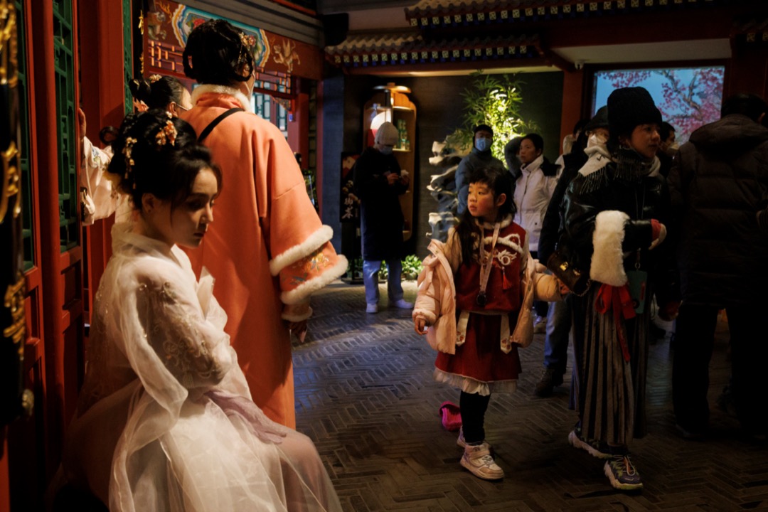 2023年1月23日,中国北京,一名女孩望著餐厅外穿传统服装的表演者。