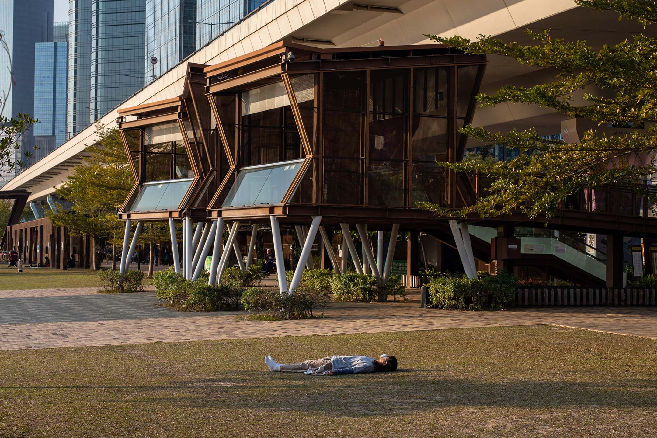 2022年3月3日,一名戴著口罩的人躺在香港观塘海滨长廊的草地上。