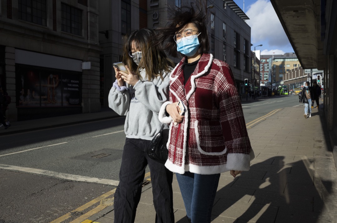 2022年2月9日,英国列斯市,两名戴口罩的女子在街道上走过。