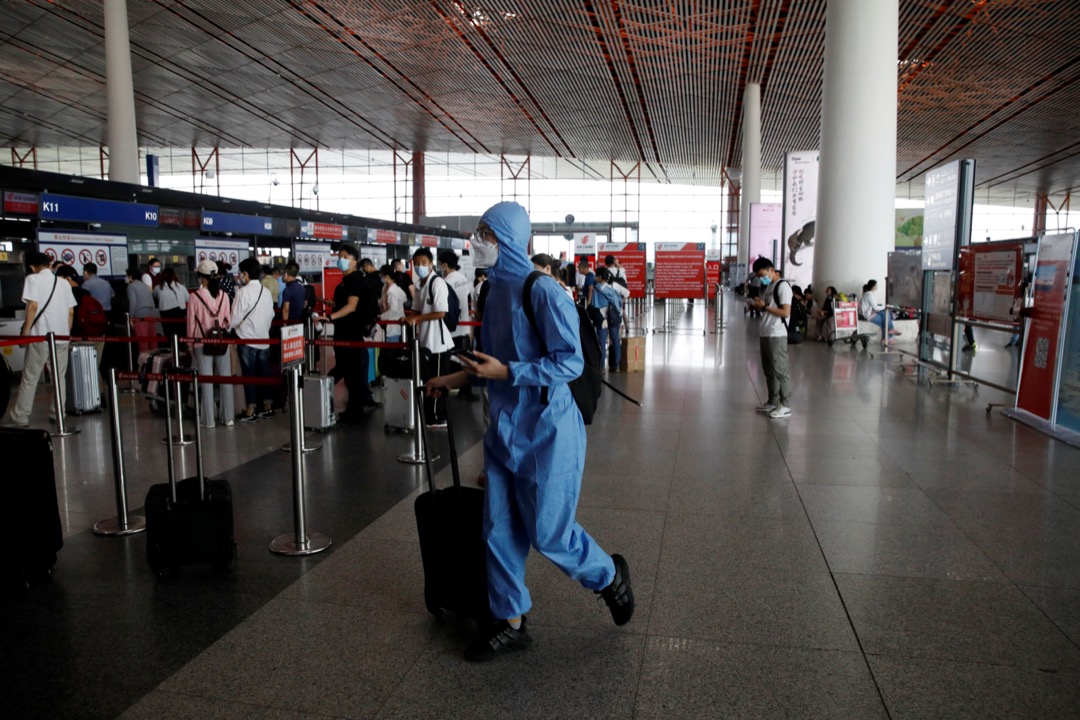2020年6月17日,中国北京首都机场,一名穿保护衣的旅客在机场大堂走过。
