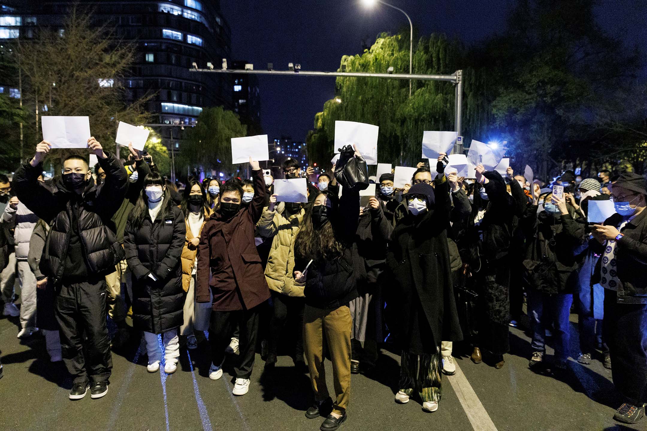 2022年11月27日,北京,乌鲁木齐火灾遇难者纪念活动期间,人们聚集在一起守夜并举著白纸抗议。