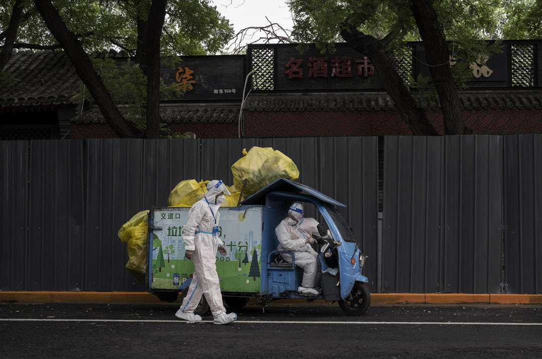 2022年6月28日,北京穿著防護服的環衛工人沿著隔離柵欄將垃圾帶走,