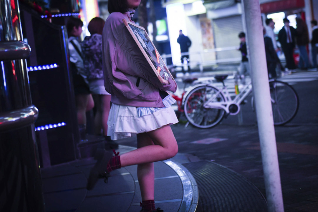 日本东京新宿区,一名女子在街上手持酒吧的广告牌宣传。