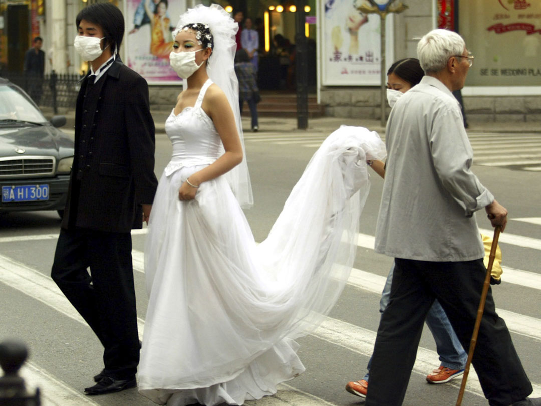 2003年5月6日,中國武漢,戴口罩的新婚夫婦過馬路。
