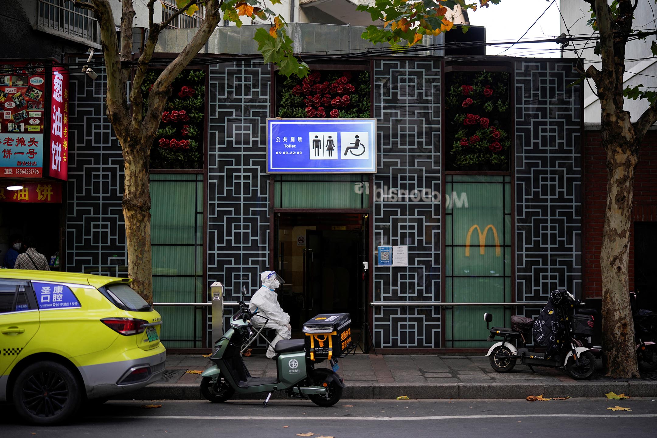 2022年11月21日,上海疫情期間,一名身穿防護服的工作人員在公共廁所外守望。