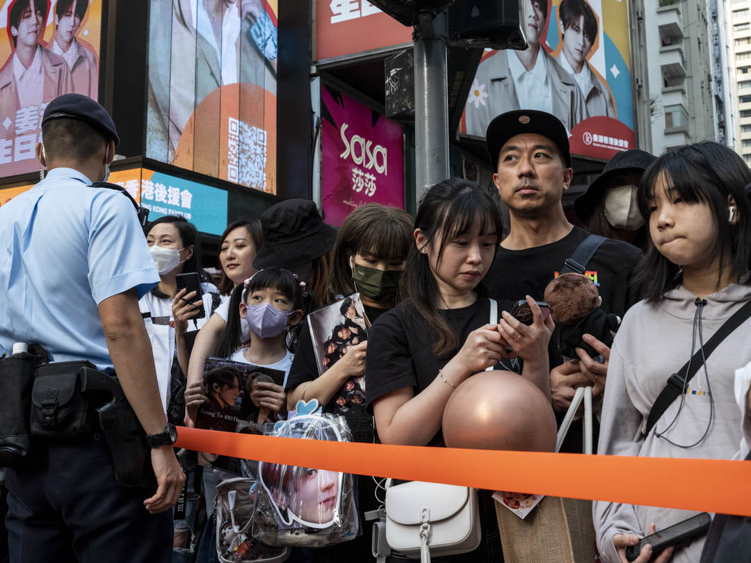 2023年5月1日,香港樂團Mirror的姜濤24歲生日,過萬名粉絲聚集在銅鑼灣的路旁,等待「姜濤號」電車,警察拉起橙帶以防他們衝出馬路。攝:林振東/端傳媒
