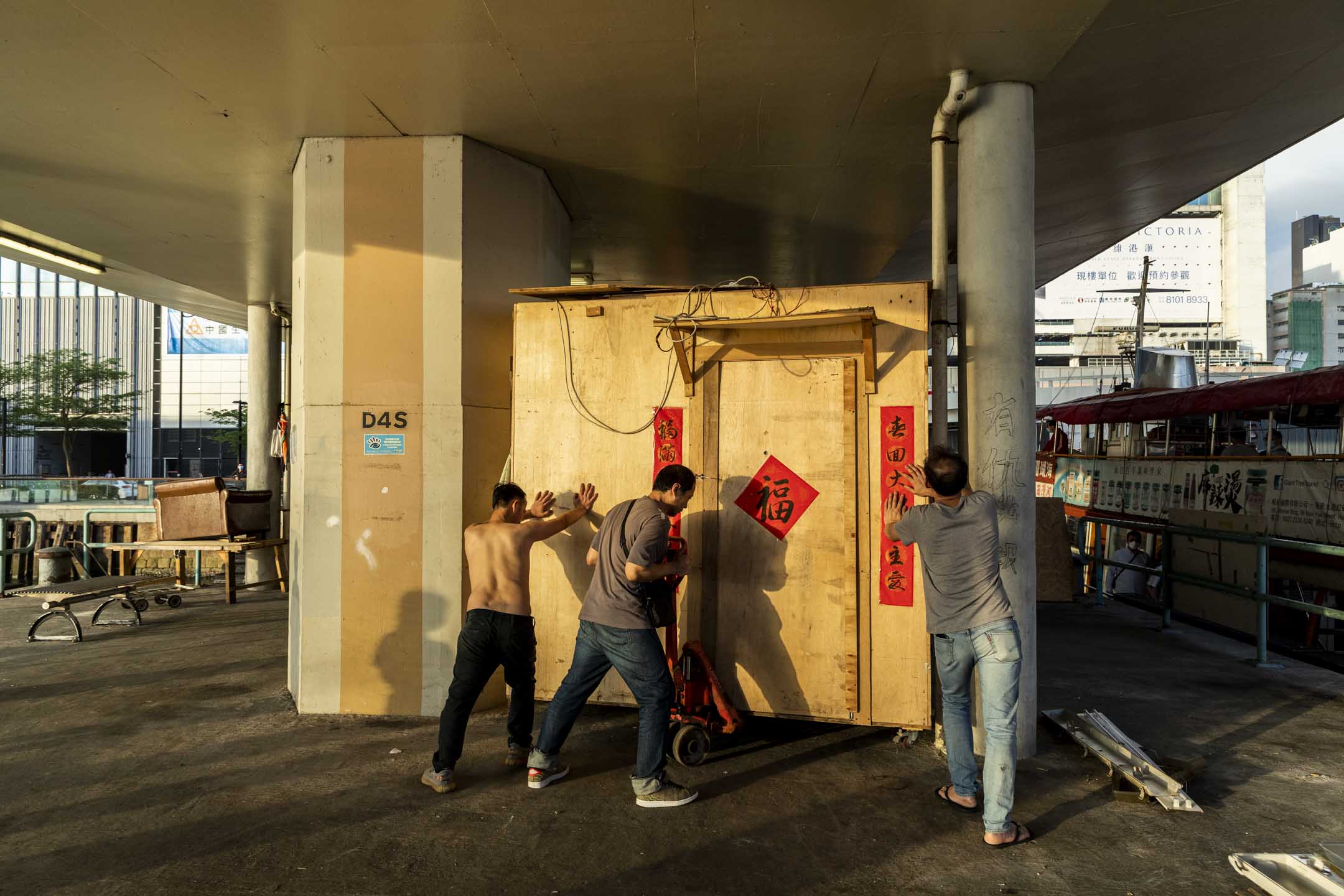 街友合力将其中一间可移动有轮的木屋推向空地。摄:林振东/端传媒