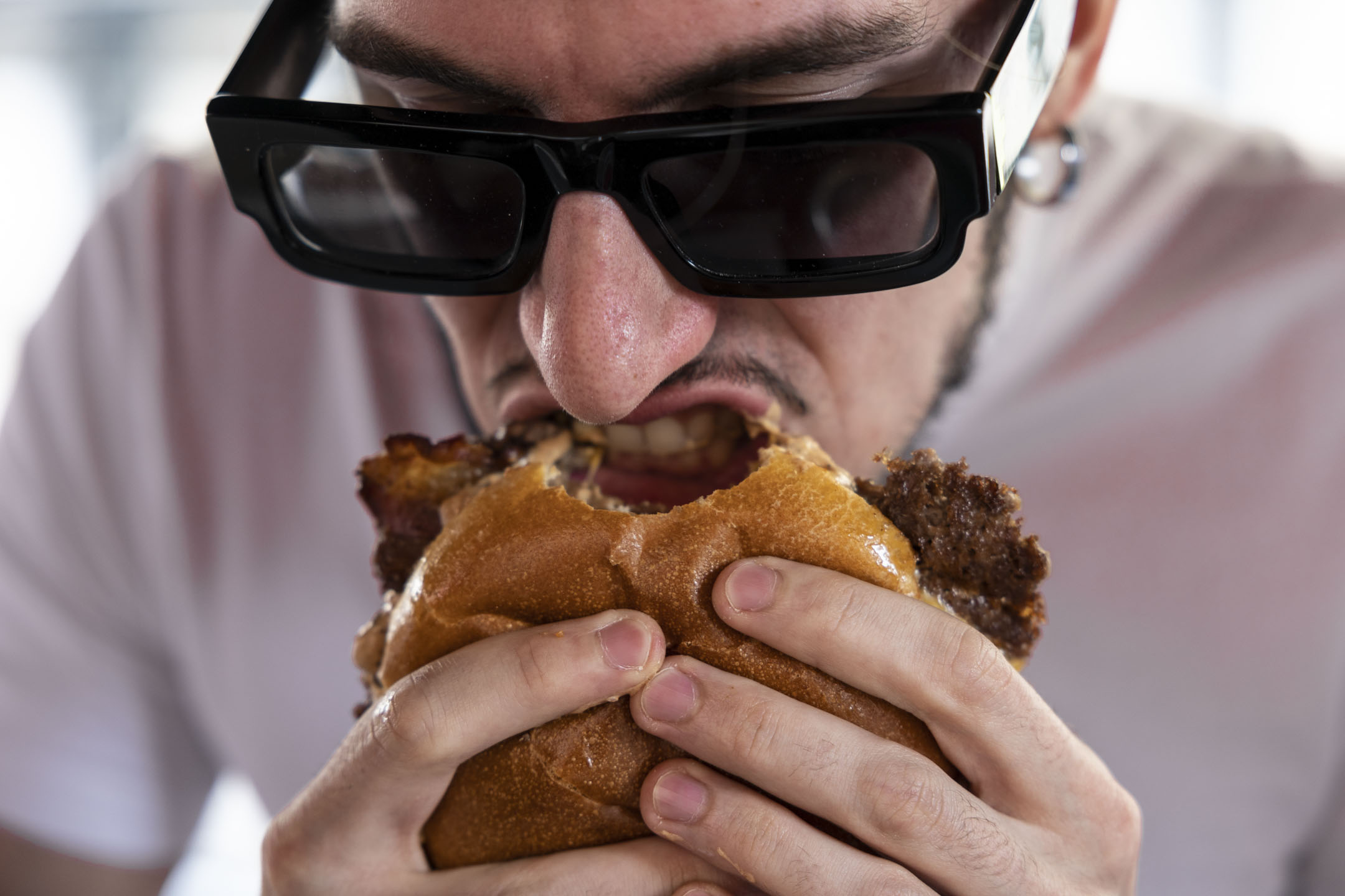 2023年5月28日,一名男子在意大利米蘭的 Meat Crew 快餐店咬培根芝士漢堡。攝:Emanuele Cremaschi/Getty Images