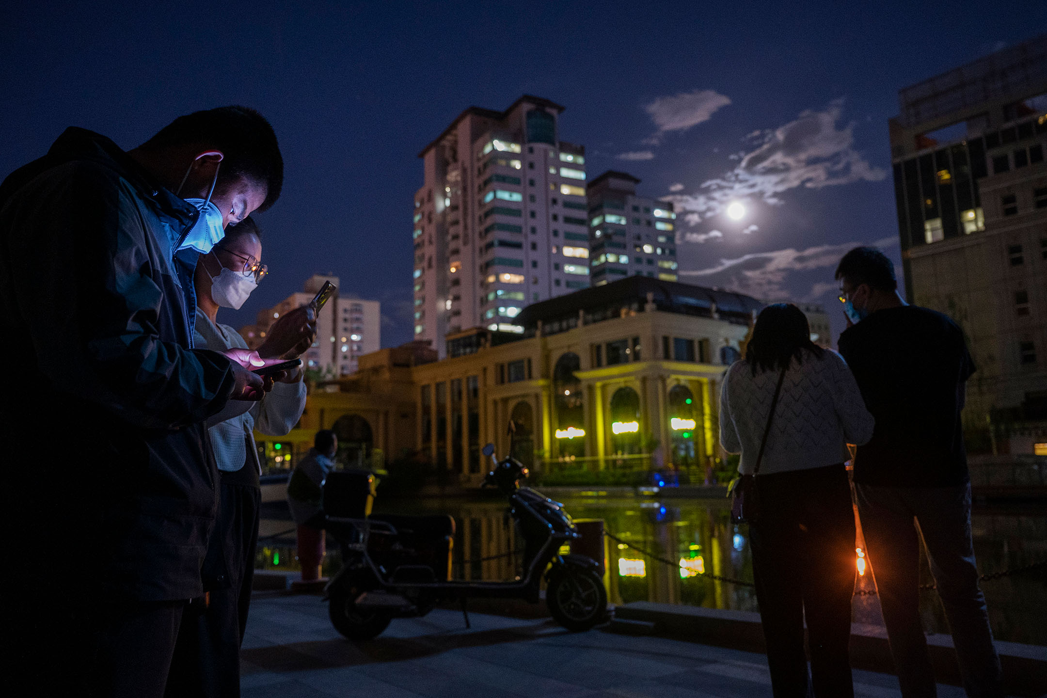 2022年5月15日,中國北京,疫情防控期間,市民在街道上看手機。攝:Kevin Frayer/Getty Images