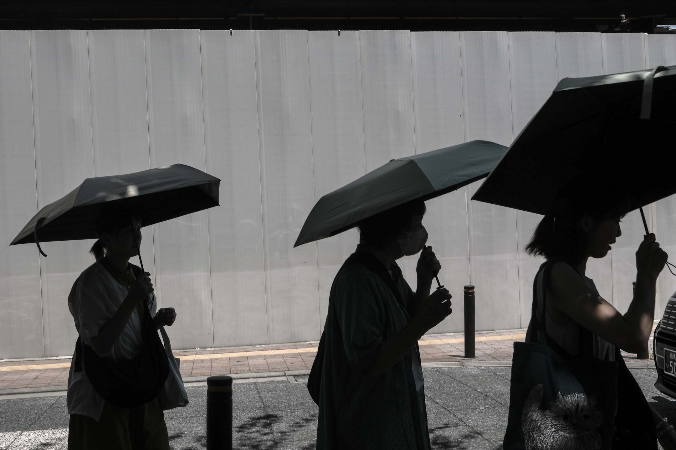 2023年7月10日,日本東京,行人在遮陽傘下躲避陽光。攝:Soichiro Koriyama/Bloomberg via Getty Images