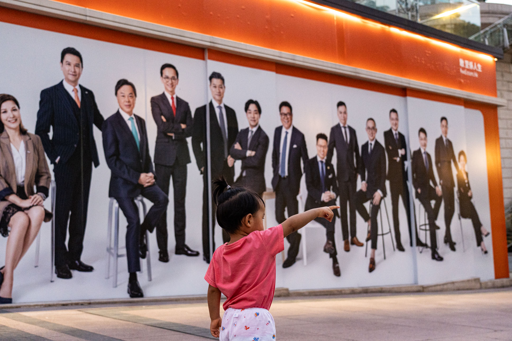 2023年7月12日，香港尖沙咀，小朋友在保险公司的广告牌前拍照。摄：Ryan Lai/端传媒