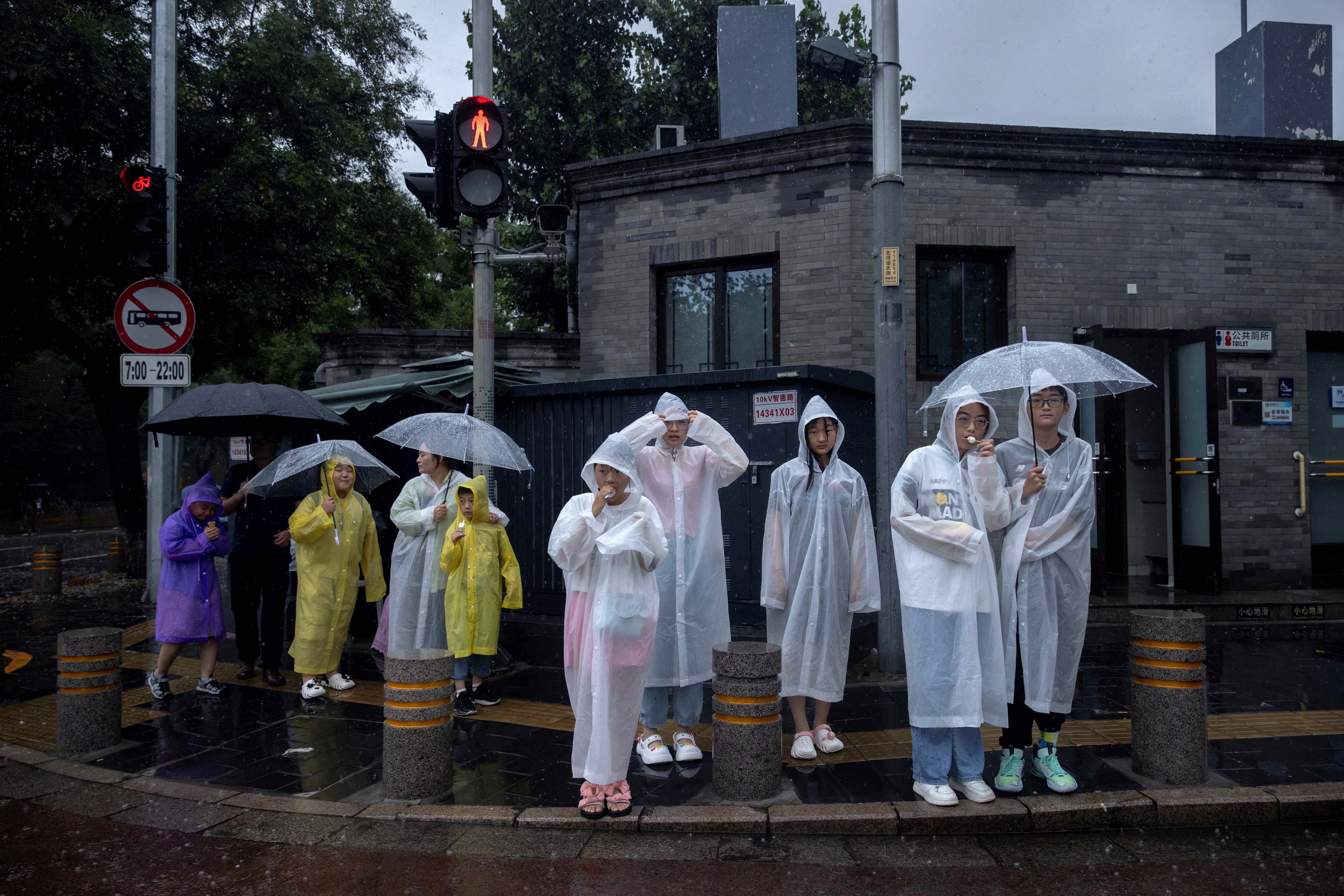 2023年7月30日,北京,旅游区内的人们穿著雨衣。摄:Thomas Peter/Reuters/达志影像