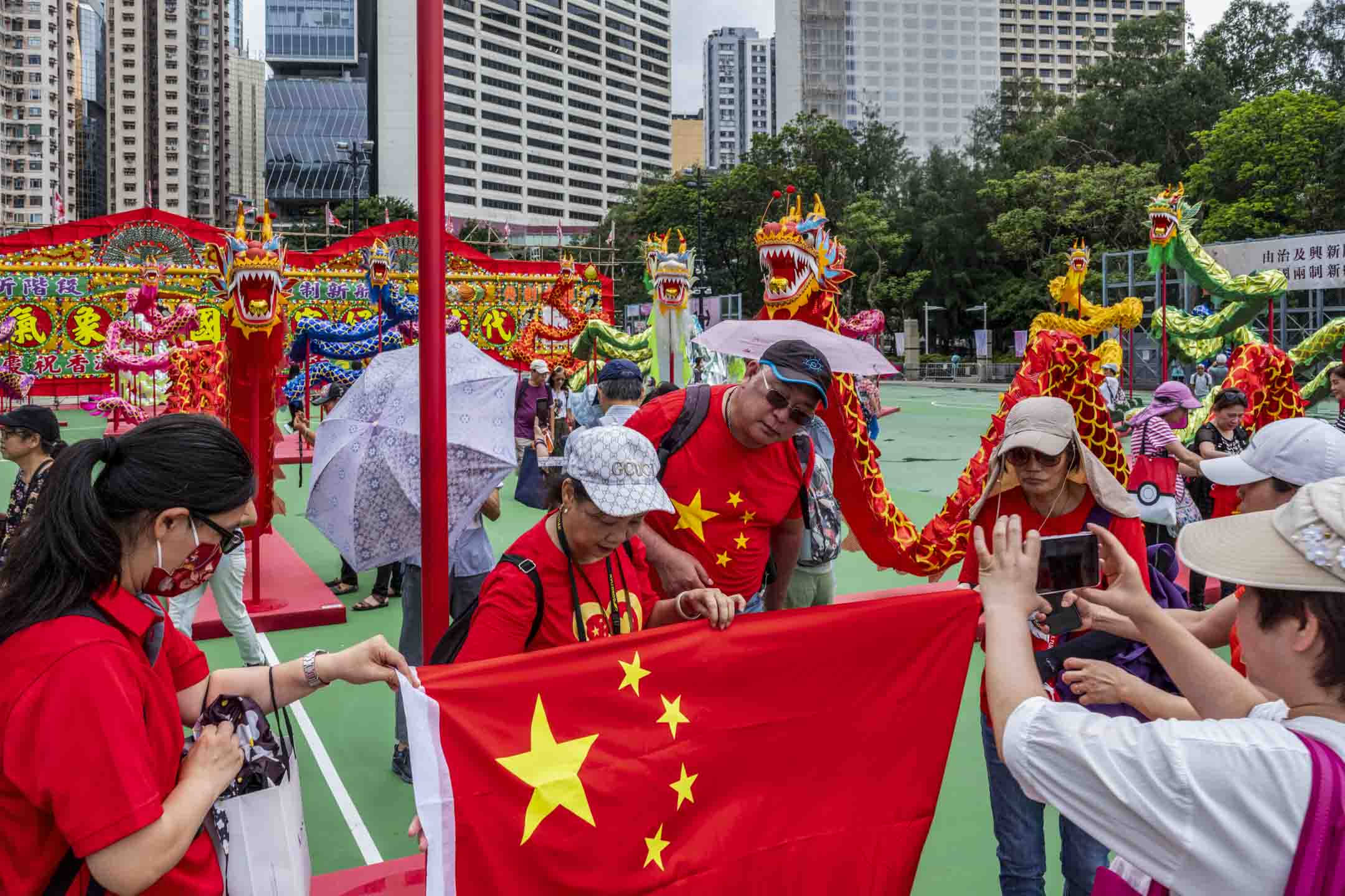 2023年6月30日,維園「慶祝香港回歸祖國二十六週年」慶祝活動,現場有本地特色大型花牌配合26條傳統舞龍,市民帶同國旗拍照。攝:林振東/端傳媒