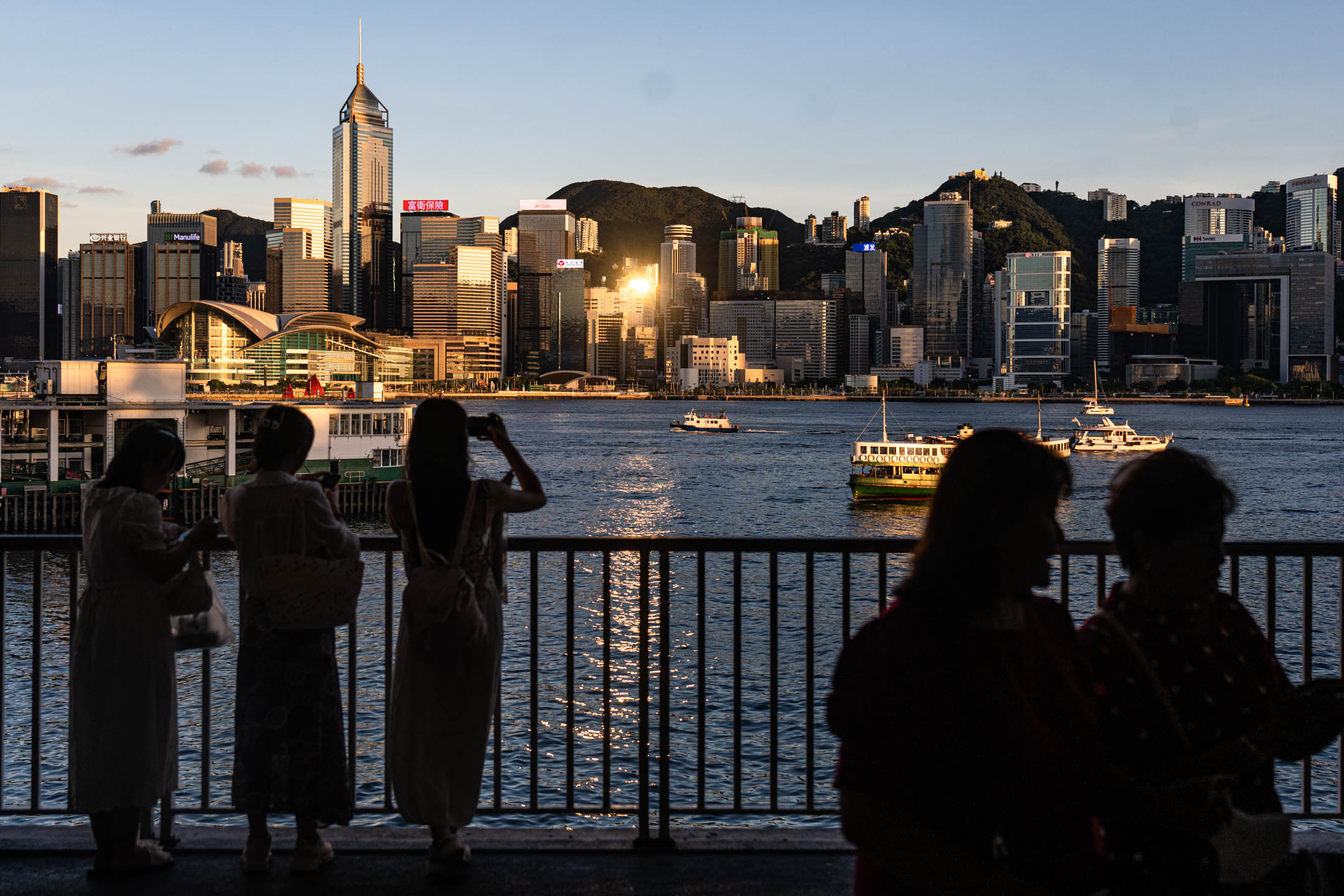 2023年7月12日,香港,游客在尖沙咀海旁,用手机拍下维多利亚港留念。摄:Ryan Lai/端传媒