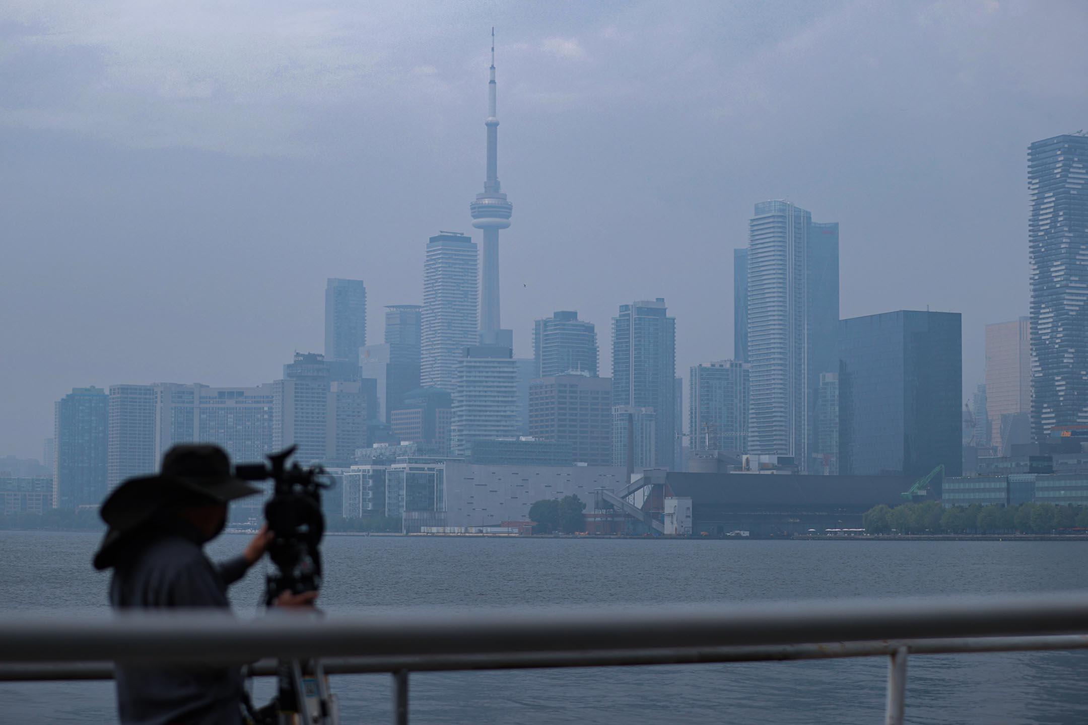 2023年6月30日,一名記者拍攝多倫多朦朧的天際線。攝:Lance McMillan/Toronto Star via Getty Images