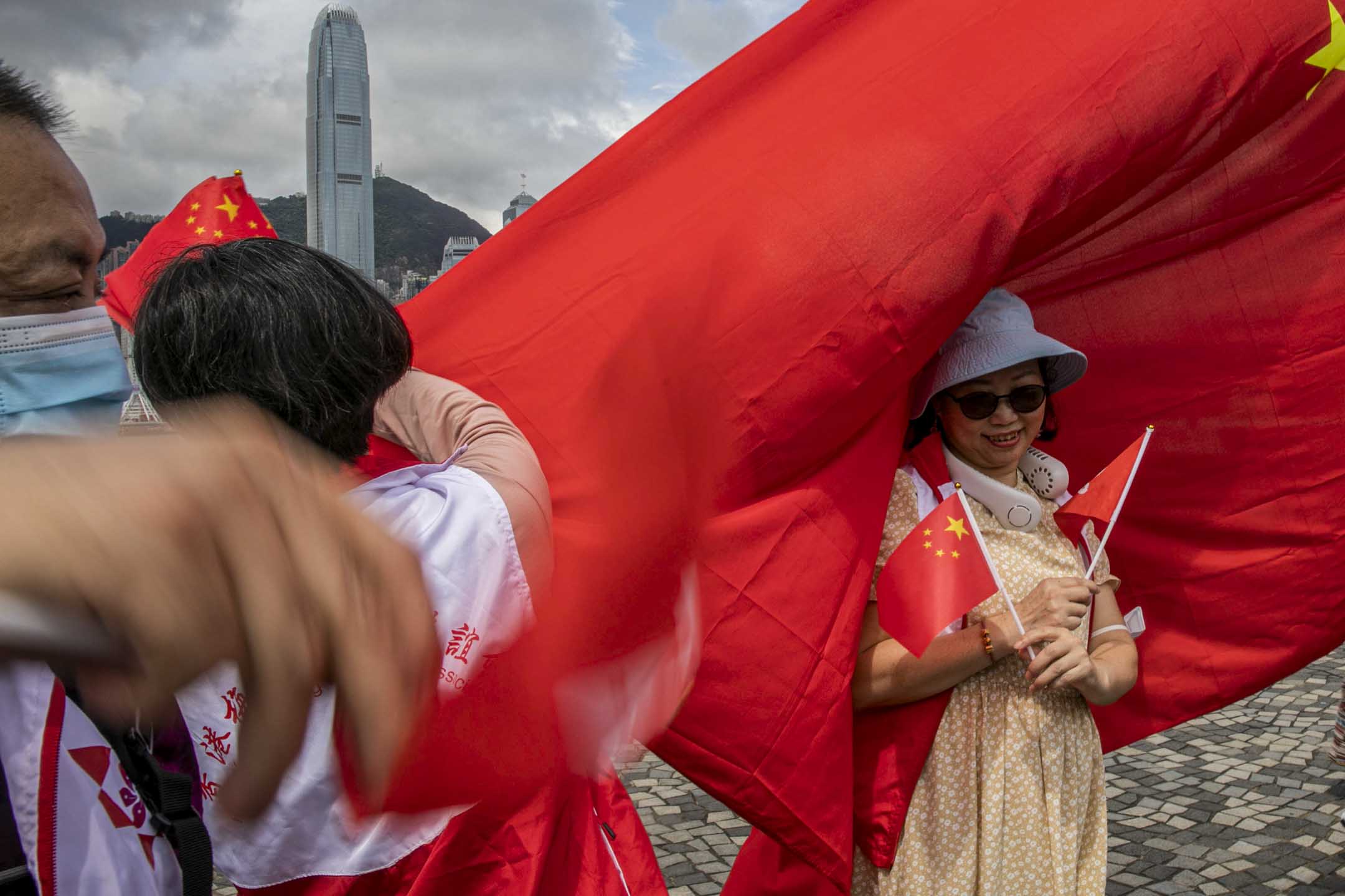 2023年7月1日,尖沙咀,市民在海傍手持國旗拍照。攝:陳焯煇/端傳媒