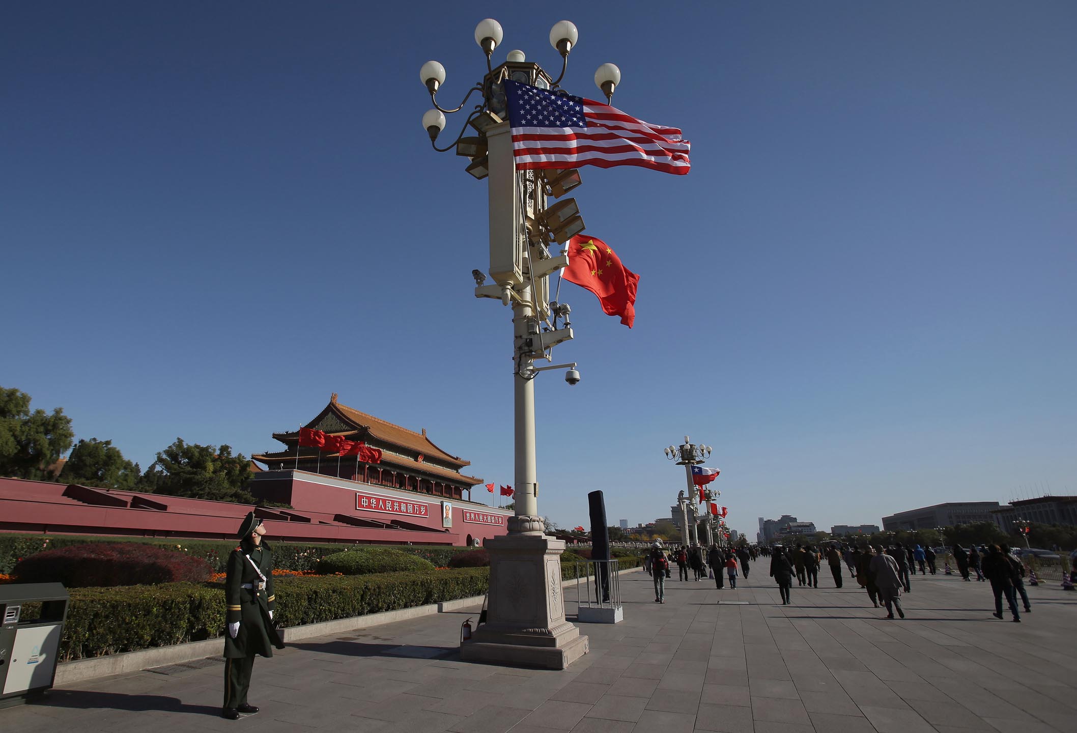 2014年11月12日，中國北京，一名軍人看著旗杆上的國旗及美國國旗。攝：Aaron Favila/AP/達志影像