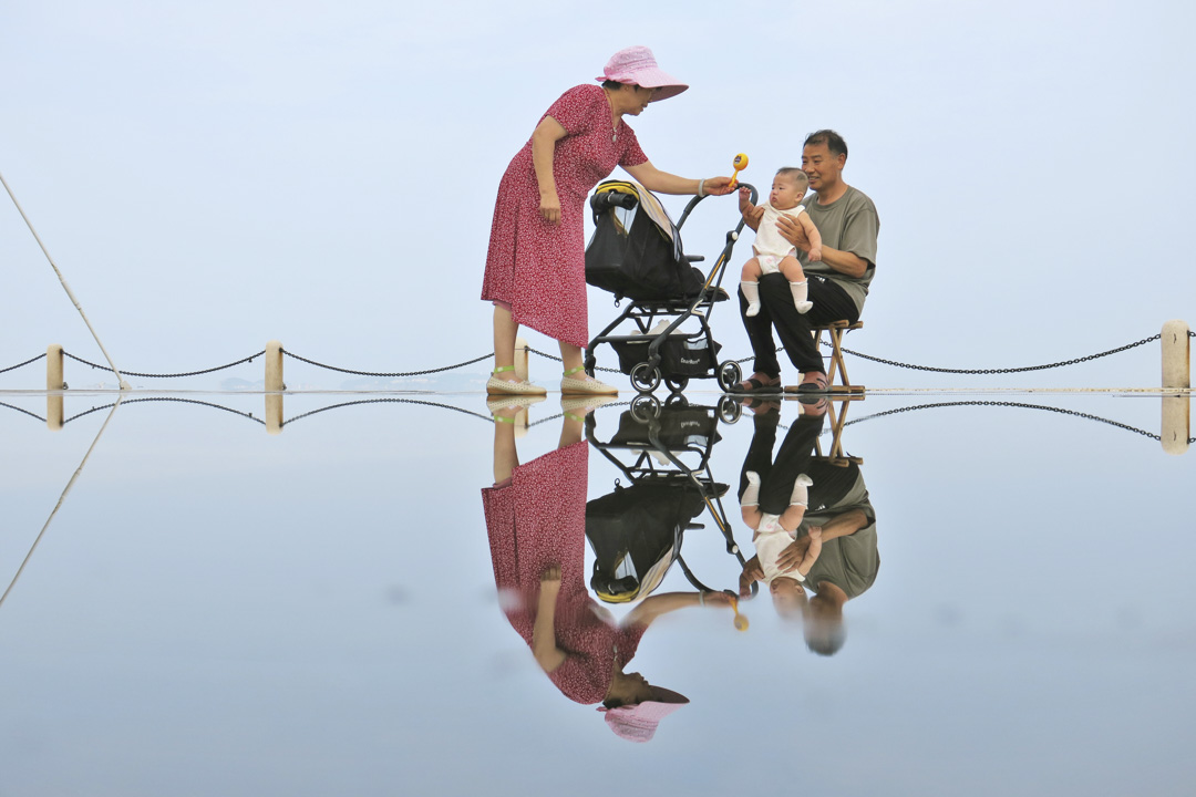 2022年7月29日,中国山东省烟台市,一对老夫妇在逗孙子。摄:Tang Ke/VCG via Getty Images