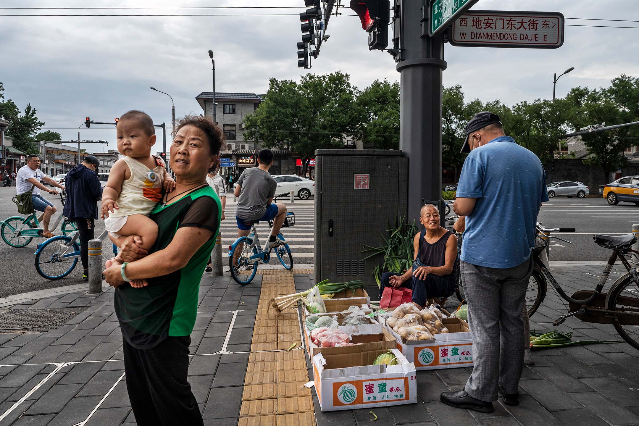 2022年6月28日，中國北京， 一名女子站在街頭上抱著孩子。攝：Kevin Frayer/Getty Images