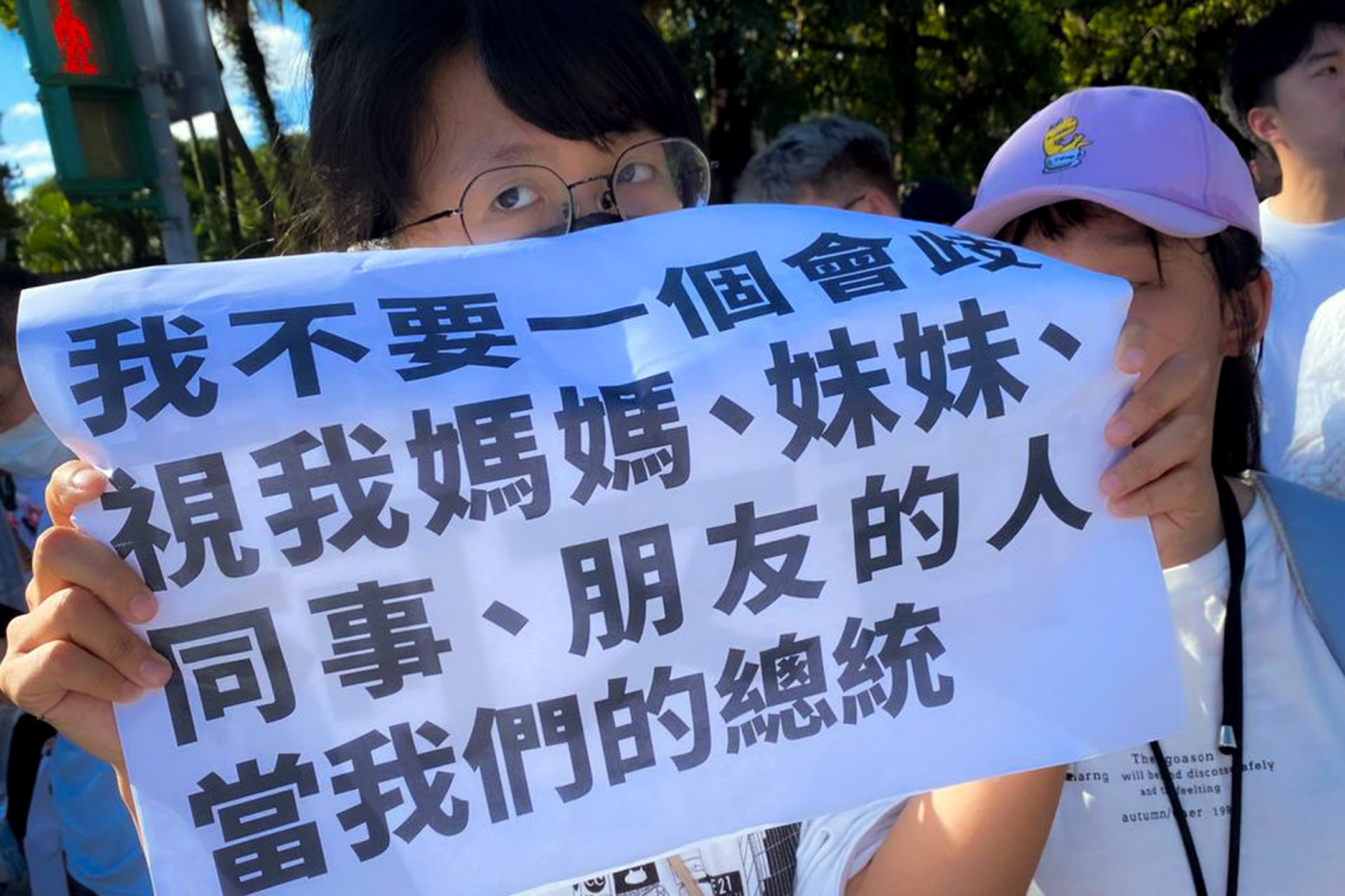 2023年7月16日,「公平正義救台灣」遊行,阿楠手舉著數張A3大小的白紙,上頭印有「年輕人不需要柯文哲」、「我不要一個會歧視我媽媽、妹妹、同事、朋友的人當我們的總統」,以及柯文哲過去各種歧視女性的發言紀錄。攝:許伯崧/端傳媒