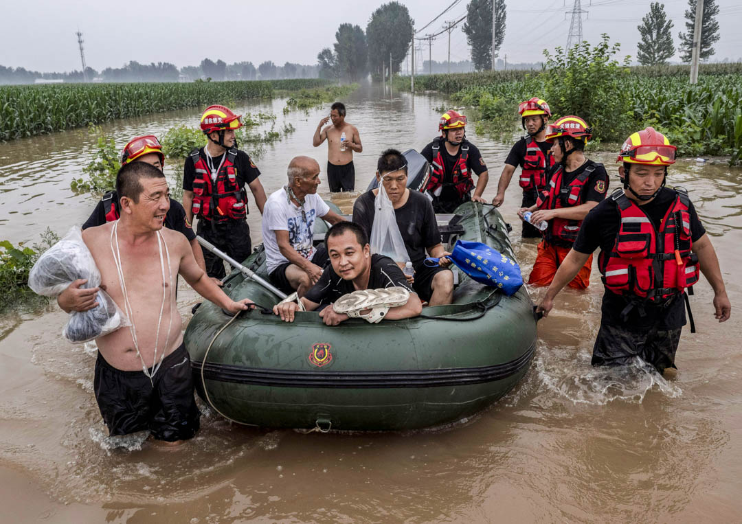2023年8月3日,中国河北涿州附近被洪水淹没的地区,救援人员帮助当地居民以船安全抵达安全地带。摄:Kevin Frayer/Getty Images