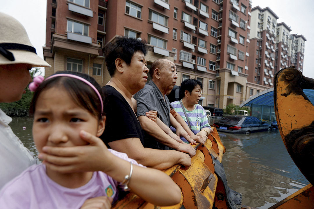2023年8月3日,中国河北涿州,台风带来的降雨和洪水过后,人们站在被淹没的住宅区疏散。摄:Tingshu Wang/Reuters/达志影像