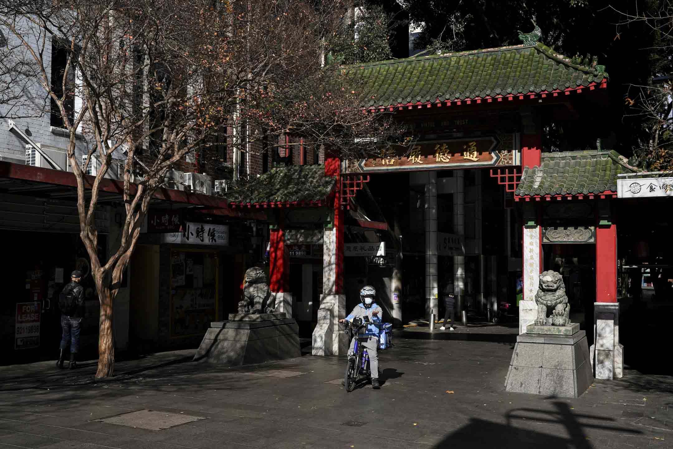 2021年6月26日,澳洲悉尼,為期兩週封鎖的第一天,一名戴著口罩的外賣送餐員穿過平時繁忙的唐人街中心。攝:Loren Elliott/Reuters/達志影像