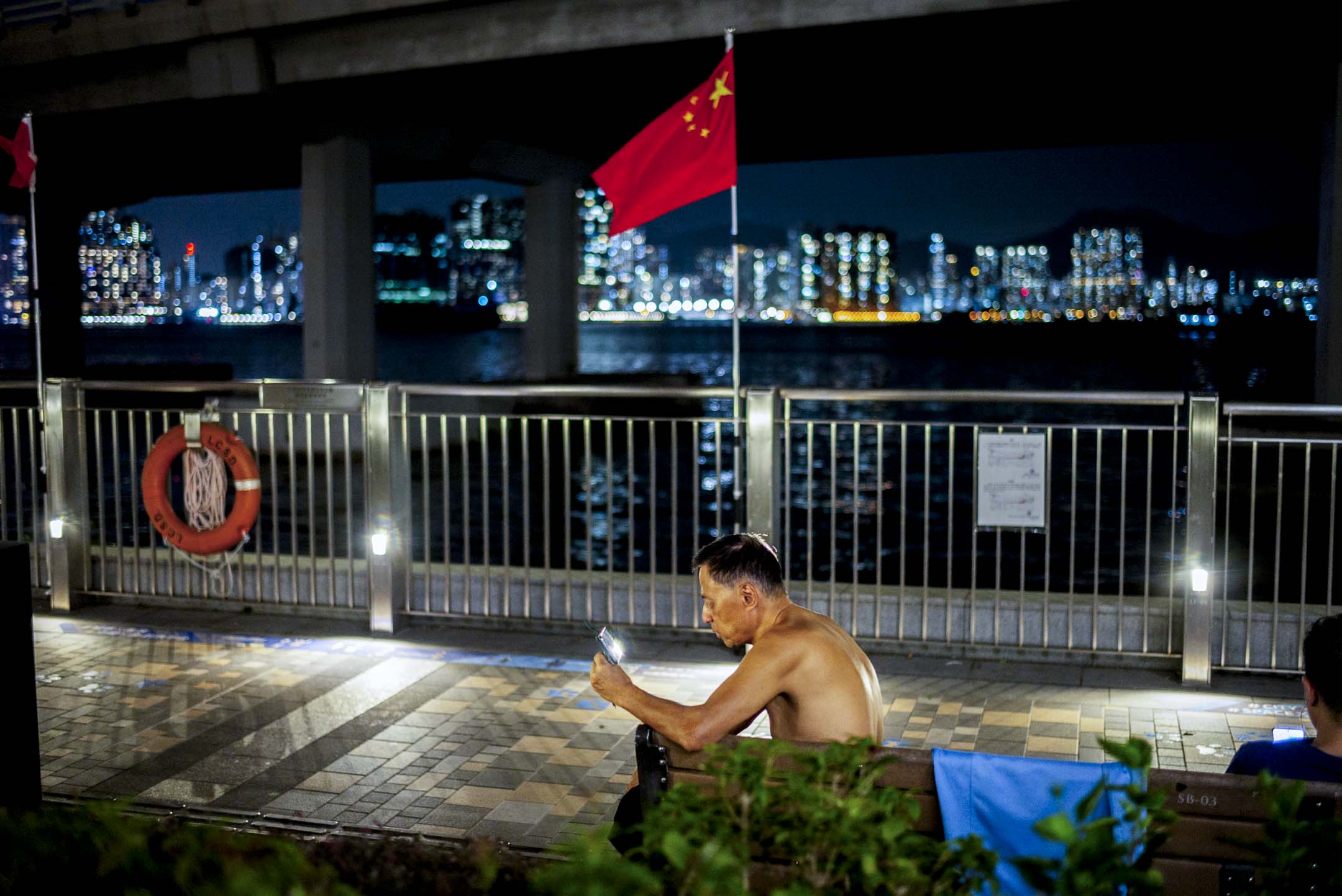 北角码头,一位脱去上衣的男士观看手机。摄:林振东/端传媒