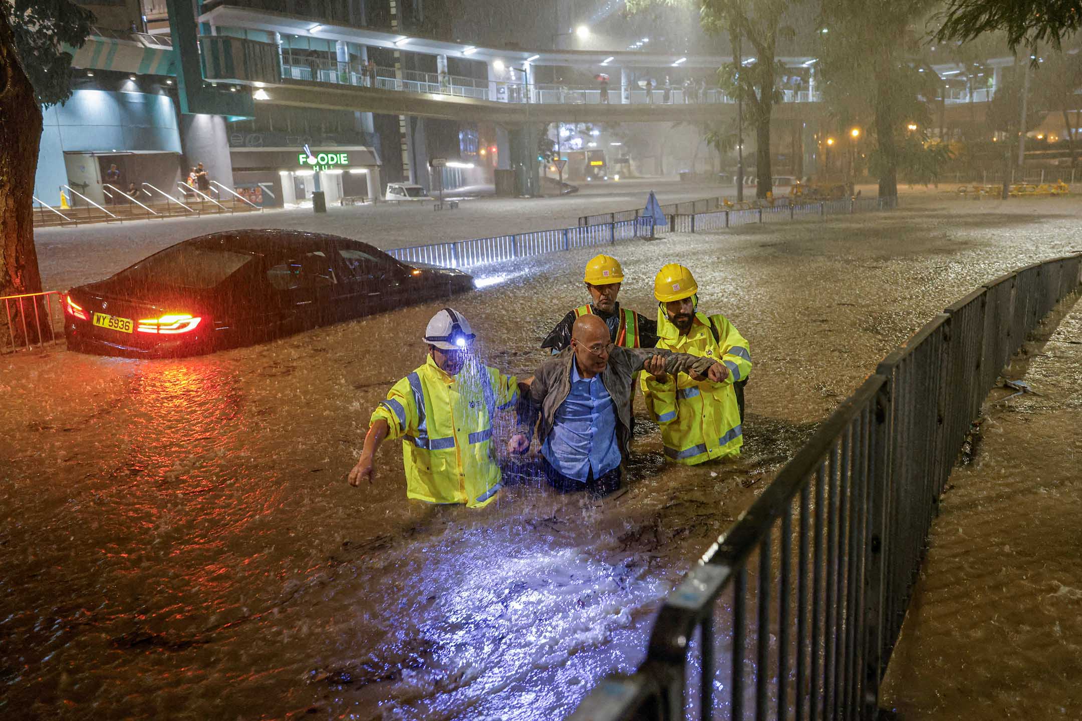 2023年9月8日,香港,大雨下,管理排水系统的人员协助一名因洪水被困的司机前往安全地点。摄:Tyrone Siu/Reuters/达志影像