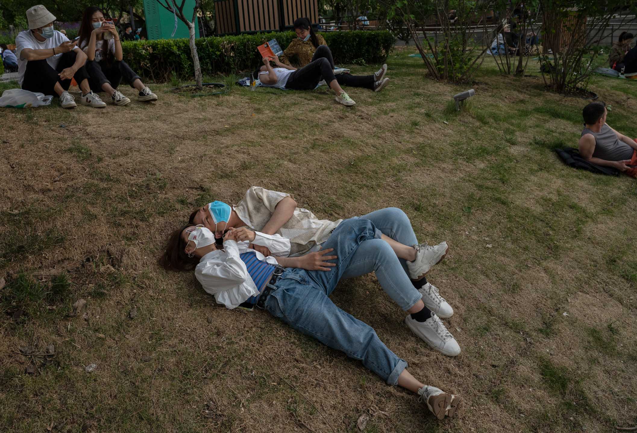 2022年5月15日，中國北京，一對情侶躺在公園草地上。攝：Kevin Frayer/Getty Images
