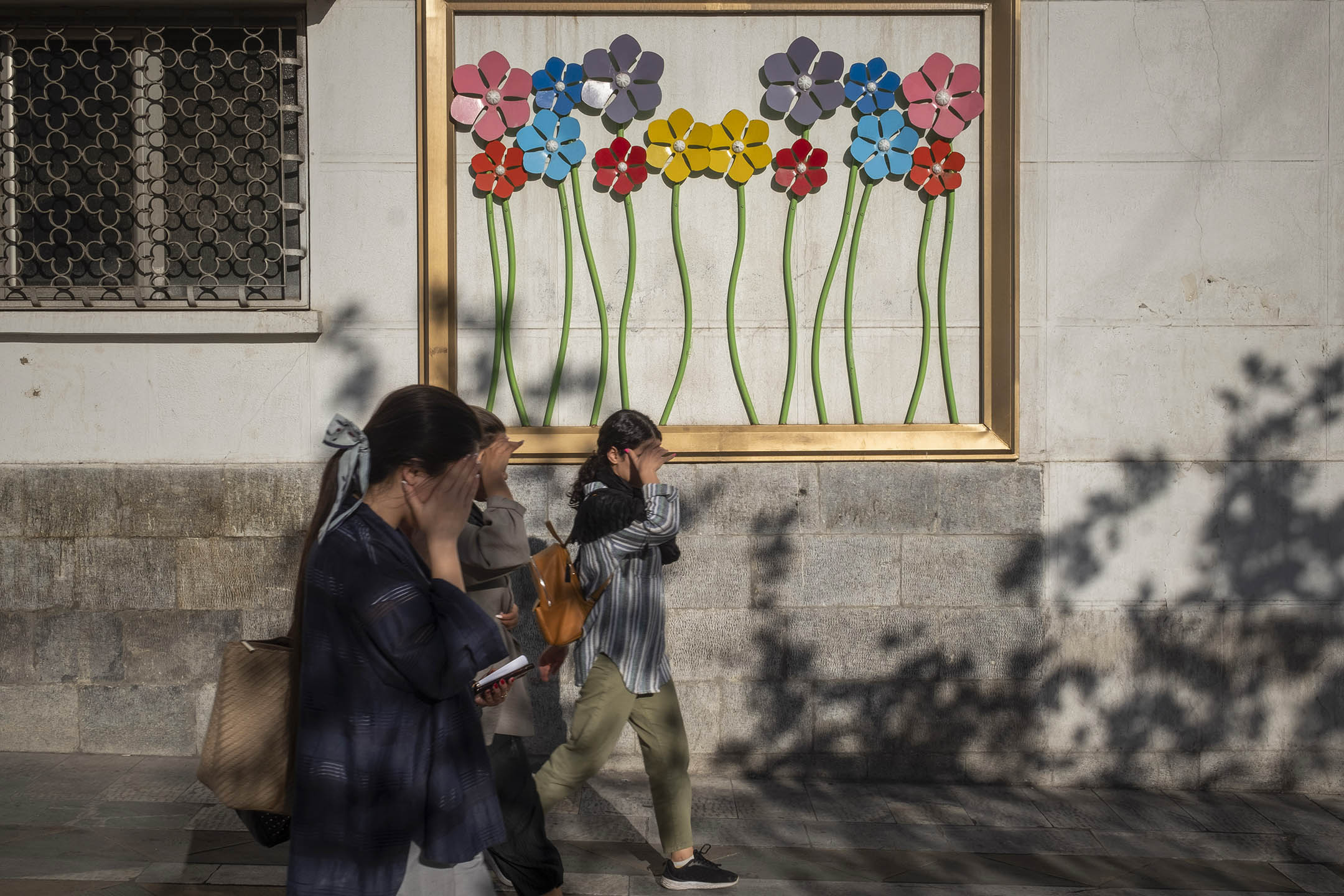2023年9月12日,伊朗女生遮著脸沿著德黑兰市中心的一条大道行走。摄:Morteza Nikoubazl/NurPhoto via Getty Images