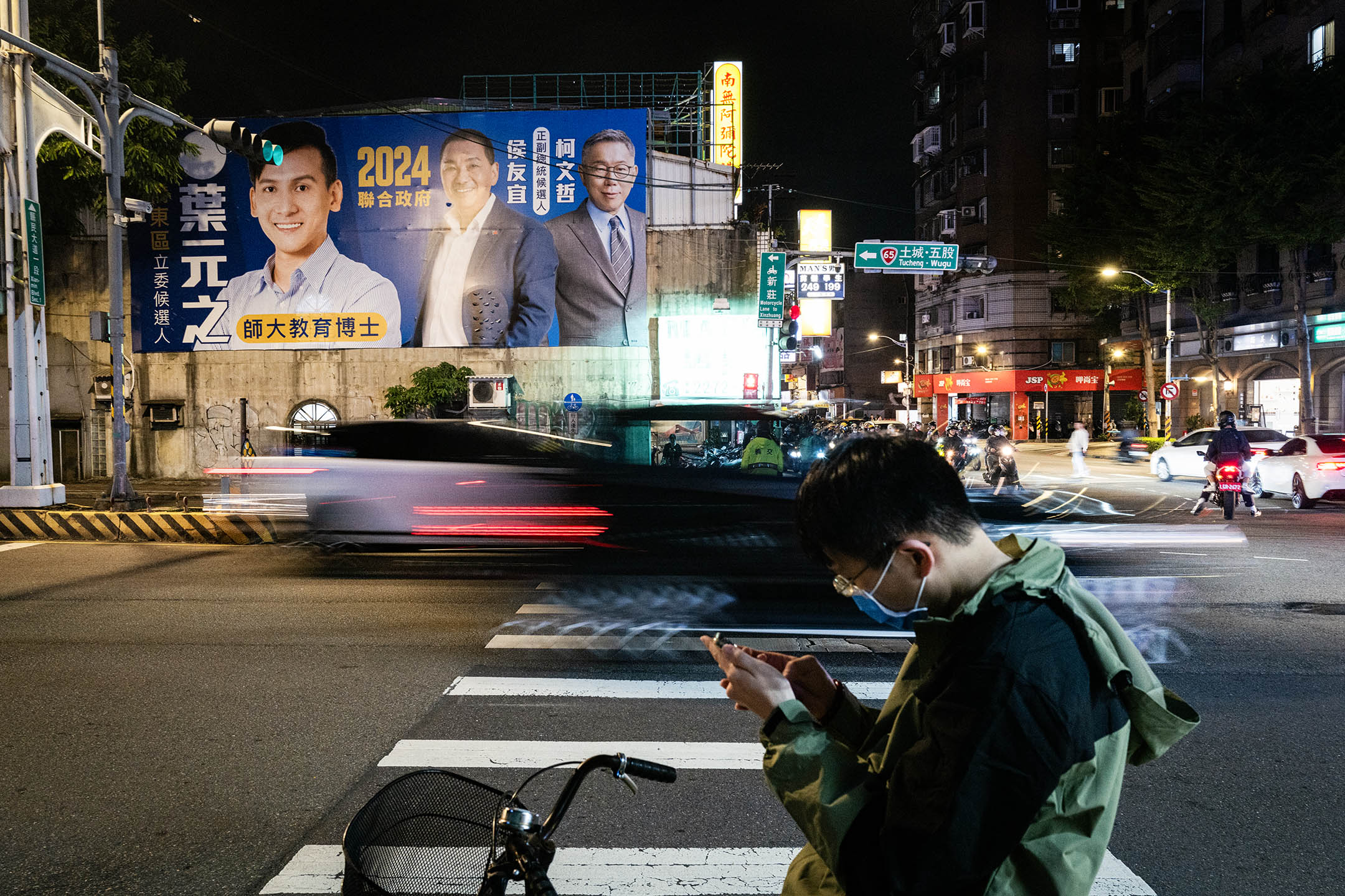 2023年10月25日,板桥,一名国民党立委候选人在广告板上印上柯文哲和侯友宜的肖像。摄:陈焯辉/端传媒